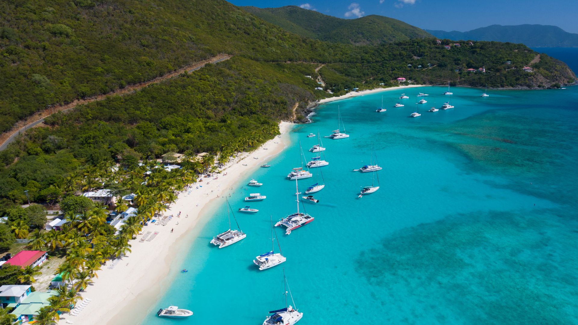 Aerial view of White Bay on Jost Van Dyke with white sand, anchored catamarans, and palm-fringed beach